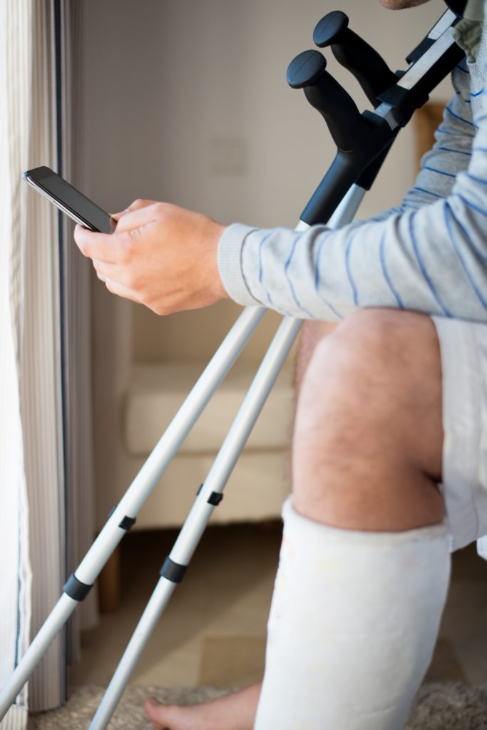 Image of a man with cast on leg looking at his phone | Santa Barbara County Auto & Bicycle Accident Lawyer